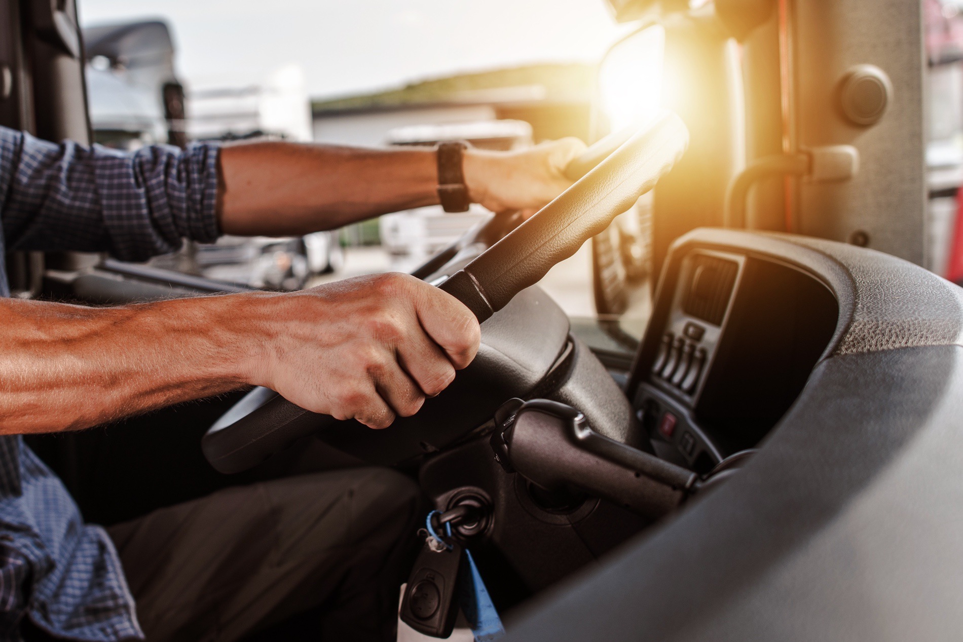 A truck driver holding the steering whel of his truck.
