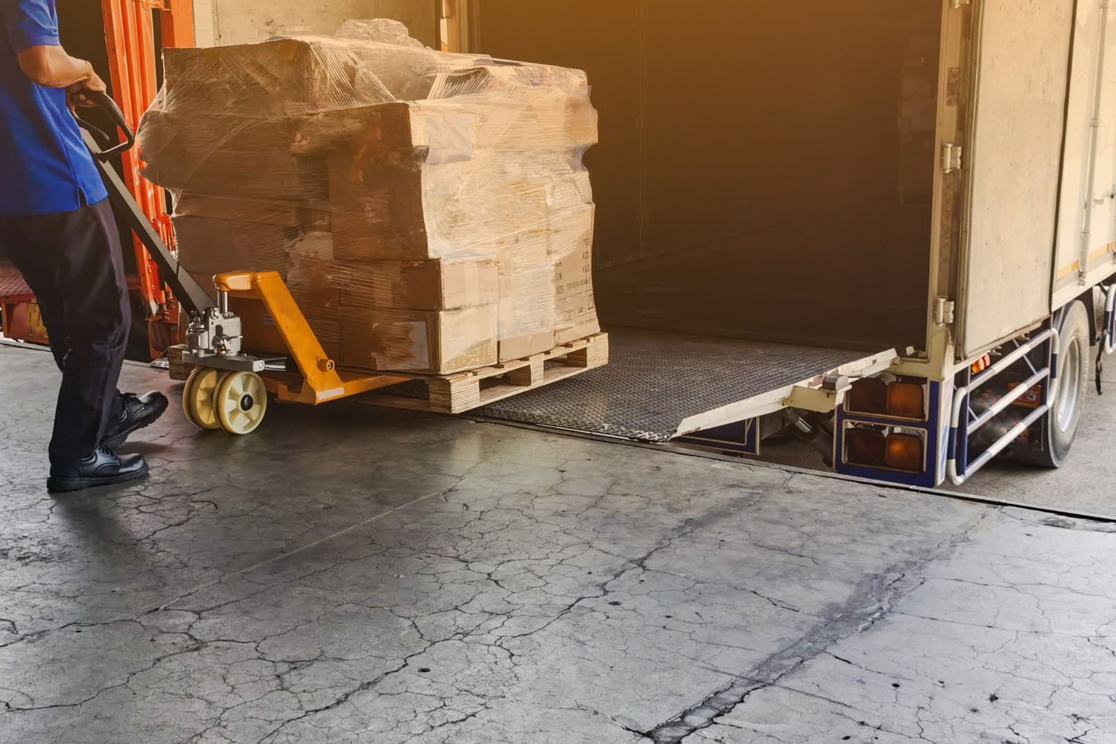 a man using a pallet jack to pull a pallet out of a box truck