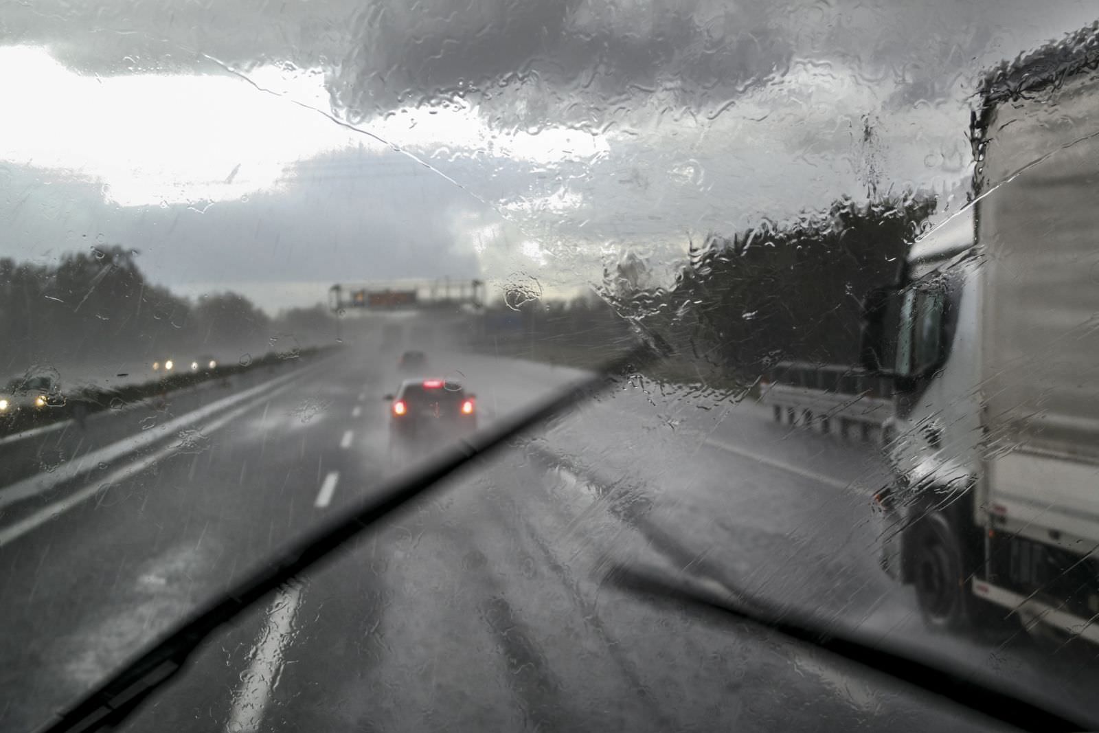 looking out through the windshield of a semi-truck that is blurry from rain